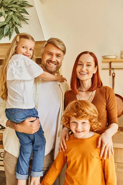 Pais alegres com crianças adoráveis olhando para a câmera na cozinha moderna acolhedora, conexão emocional — Fotografia de Stock