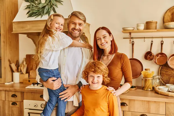 Fröhliche Kinder mit lächelnden Eltern, die in der modernen Küche in die Kamera schauen, gemütliches Wohnumfeld — Stockfoto