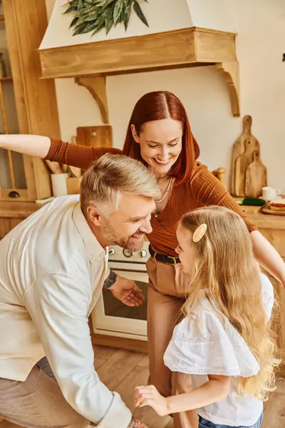 Freudige Eltern mit entzückender Tochter, die Spaß hat und in der gemütlichen Küche spielt, verbindende Momente — Stockfoto