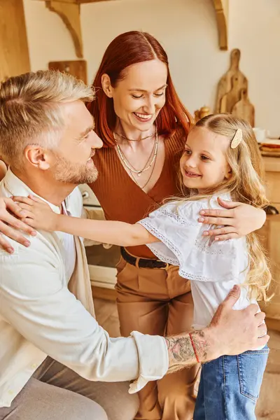 Genitori premurosi con figlia adorabile che abbraccia in cucina accogliente a casa, legando momenti familiari — Foto stock