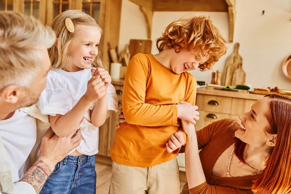 Pais felizes cócegas crianças excitadas e se divertindo na cozinha moderna em casa, momentos de ligação — Fotografia de Stock