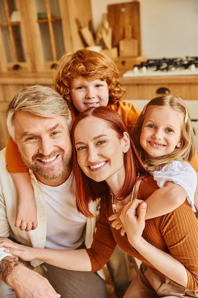 Happy parents and children embracing and smiling at camera in modern kitchen, cherished moments — Stock Photo