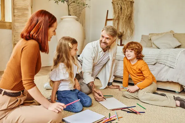 Fröhliche Eltern und Kinder, die gemeinsam auf dem Fußboden im modernen Wohnzimmer zeichnen und Kreativität ausdrücken — Stockfoto