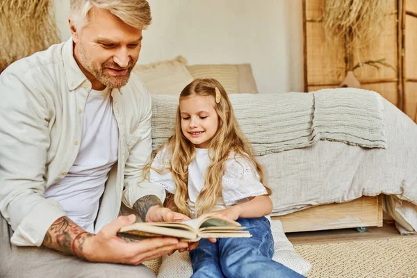 Pai carinhoso e filha bonito sentado no chão no quarto e livro de leitura, aprendendo juntos — Fotografia de Stock