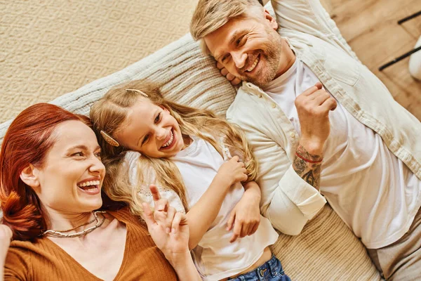 Top view of cheerful parents with cute daughter lying down and having fun on bed, relaxation time — Stock Photo