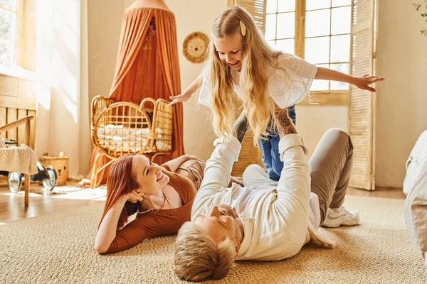 Веселая женщина смотрит на мужа, играющего с дочерью на полу в гостиной, связывающие моменты — Stock Photo