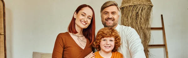 Smiling parents with redhead son sitting looking at camera in modern bedroom, horizontal banner — Stock Photo