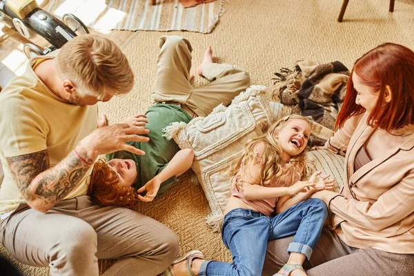Blick von oben auf Eltern, die mit unbeschwerten Kindern auf dem Boden im gemütlichen Wohnzimmer zu Hause spielen, freudige Momente — Stockfoto