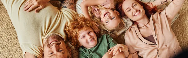 Vue de dessus des parents gais et des enfants couchés sur le sol dans le salon, bannière horizontale — Photo de stock