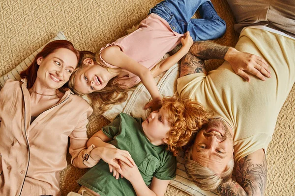 Top view of happy parents and kids lying down and on floor and having fun in modern living room — Stock Photo