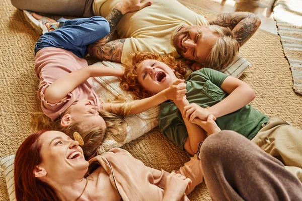 Vista de alto ângulo de pais e filhos se divertindo no chão na sala de estar moderna, momentos de ligação — Fotografia de Stock