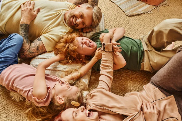 Vista ad alto angolo di genitori e bambini divertirsi sul pavimento in soggiorno moderno, momenti cari — Foto stock