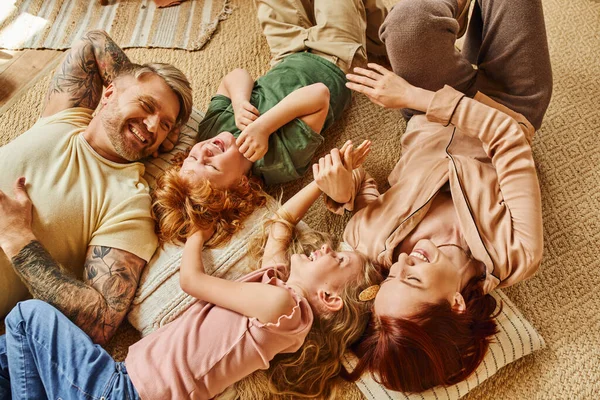 Vista dall'alto di genitori e bambini felicissimi che si divertono sul pavimento in un soggiorno moderno, momenti preziosi — Foto stock