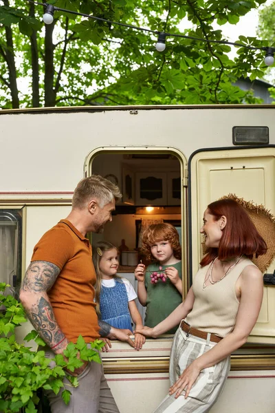 Glückliche Eltern, die sehen, wie Tochter und Sohn Spaß im Wohnwagen, Familienfreizeit und Erholung haben — Stockfoto