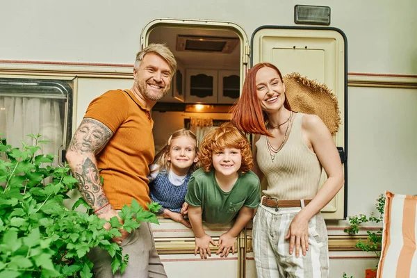 Happy couple smiling at camera near kids having fun in trailer home, relaxation time and adventure — Stock Photo