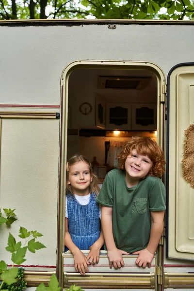 Feliz ruiva menino olhando para a câmera de reboque casa perto adorável irmã, relação irmãos — Fotografia de Stock