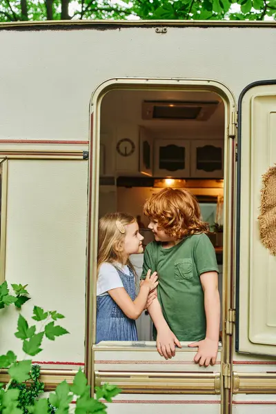 Cheerful brother and sister smiling at each inside trailer home, happiness and siblings relationship — Stock Photo