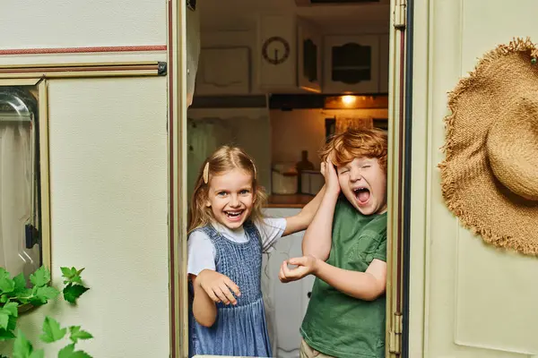 Drôles et joyeux enfants grimaçant et regardant la caméra de la maison de remorque, frère et sœur heureux — Photo de stock