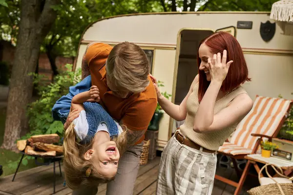 Homem brincando com a filha rindo perto de esposa feliz e casa móvel no parque de reboque, tempo de qualidade — Fotografia de Stock