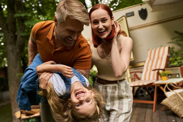 Mann amüsiert sich mit aufgeregter Tochter in der Nähe von glücklicher Frau und Handy im Trailerpark — Stockfoto