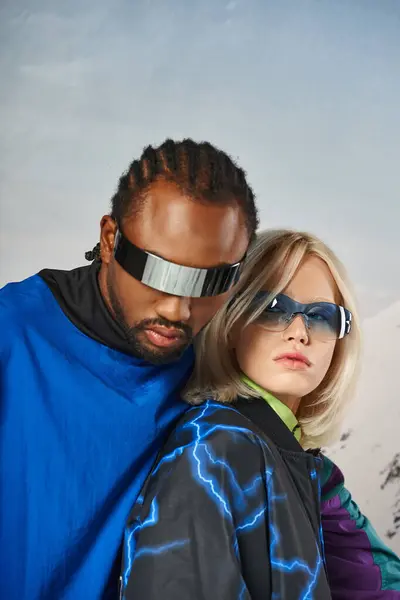 Крупним планом стильна пара в яскравих сонцезахисних окулярах, що обіймаються і дивляться на камеру, зимова концепція — стокове фото