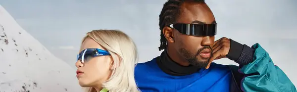 Voguish jeune couple multiculturel dans des lunettes de soleil élégantes posant ensemble, concept d'hiver, bannière — Photo de stock