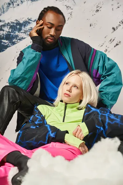 Привлекательная разнообразная пара в теплой стильной одежде, позируя вместе на снегу вместе, зимняя концепция — стоковое фото
