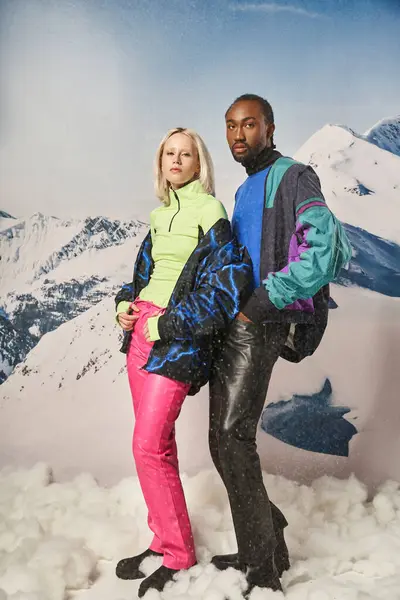 Красива мультикультурна пара в модному яскравому одязі позує на камеру разом, зимова концепція — стокове фото