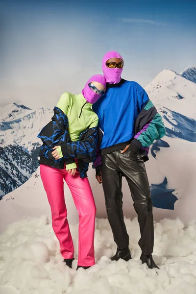 Beau couple posant ensemble portant des cagoules roses et des lunettes de soleil élégantes, concept d'hiver — Photo de stock
