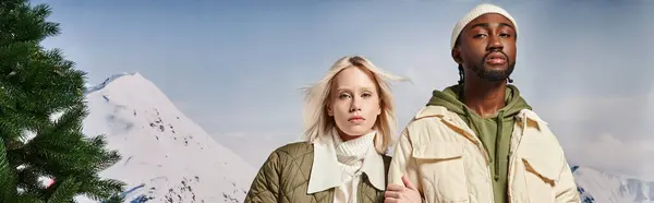 Couple multiracial à la mode posant avec la main sur le bras et regardant la caméra, concept d'hiver, bannière — Photo de stock