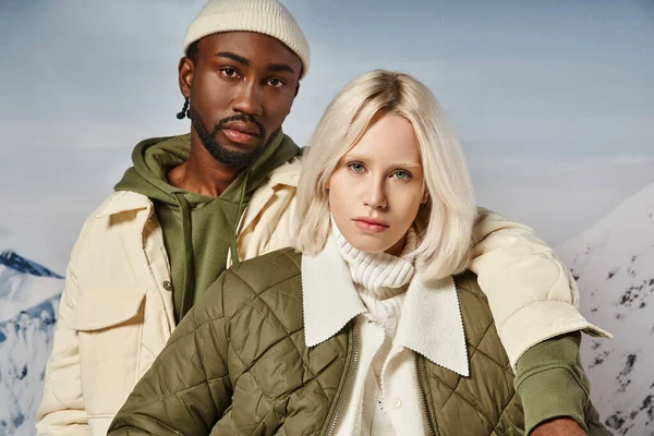 Retrato de casal multirracial voguish em traje vibrante quente olhando para câmera, conceito de inverno — Fotografia de Stock