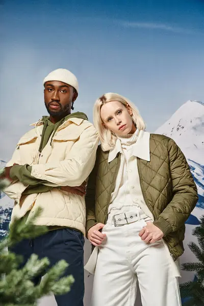 Atractiva pareja en cálidas chaquetas de invierno posando juntos sobre fondo nevado, moda de invierno - foto de stock