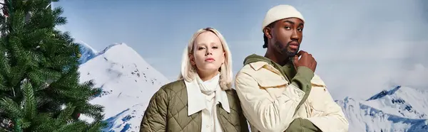 Hermosa pareja multicultural posando en chaquetas calientes y mirando a la cámara, moda de invierno, pancarta - foto de stock