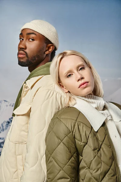 Retrato de pareja de moda en traje cálido posando espalda con espalda mirando a la cámara, moda de invierno - foto de stock