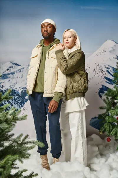 Hübsche blonde Frau in warmer Jacke umarmt ihren stilvollen Freund mit Mütze, Wintermode — Stockfoto