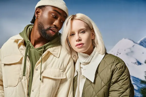 Attraktives Paar in stylischem, modernem Outfit mit schneebedecktem Berg vor der Kulisse, Winterkonzept — Stockfoto