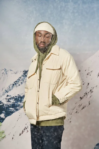 Stylischer Mann in trendiger Winterkleidung, der bei Schneefall mit den Händen in den Taschen steht, Mode und Stil — Stockfoto