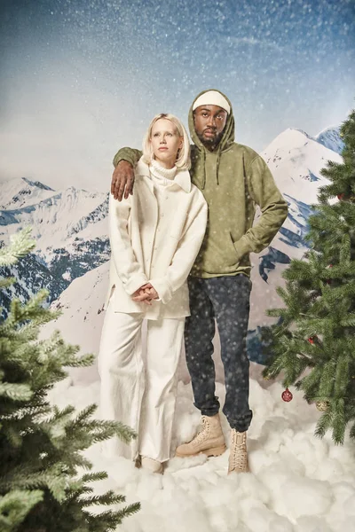 Attraente coppia posa sotto la nevicata e indossa abiti invernali alla moda, moda e stile — Foto stock