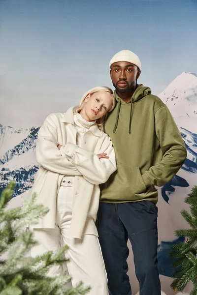 Mujer bonita con brazos cruzados junto a su novio con las manos en los bolsillos, moda de invierno - foto de stock