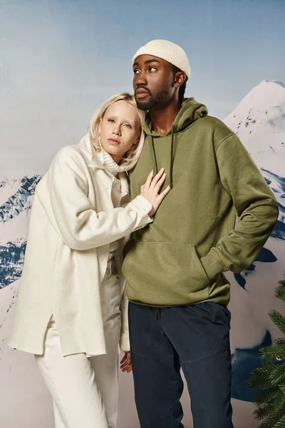Mujer rubia joven con la mano en el pecho de su novio con fondo nevado, moda de invierno - foto de stock