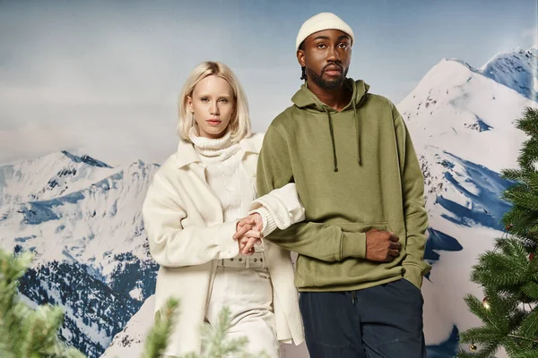 Élégante femme blonde debout avec petit ami afro-américain avec toile de fond de montagne, mode d'hiver — Photo de stock