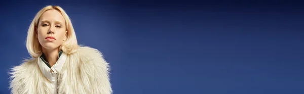 Bannière d'hiver, portrait de jeune femme en fausse fourrure blanche regardant la caméra sur fond bleu — Photo de stock