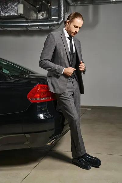 Good looking man in elegant suit with tie looking down on parking lot near his car, business concept — Stock Photo