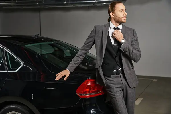 Красивий професіонал з хвостом позує поруч зі своєю машиною і дивиться вбік, бізнес-концепція — стокове фото