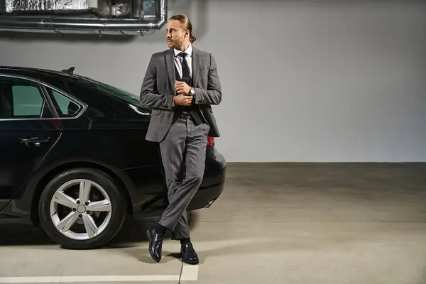 Bell'uomo in abito elegante con cravatta in posa accanto alla sua auto e guardando altrove, concetto di business — Foto stock