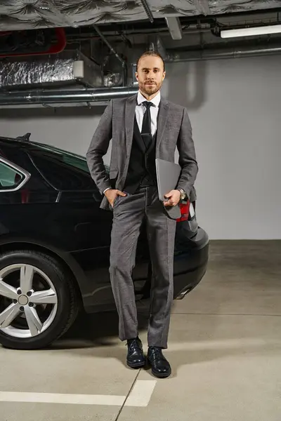 Gut aussehender eleganter Mann im schicken schicken schicken Anzug mit Laptop und Blick auf die Kamera, Geschäftskonzept — Stockfoto