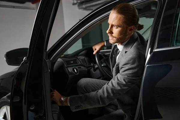 Homem elegante bonito com cabelo vermelho em terno inteligente sentado ao volante, conceito de negócio — Fotografia de Stock