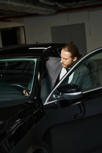 Handsome elegant man with ponytail in chic smart suit getting into his car, business concept — Stock Photo