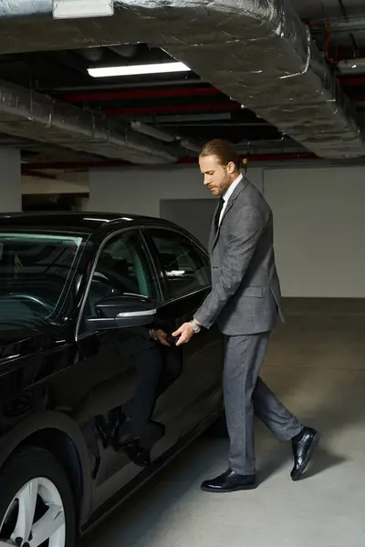 Appealing red haired man in smart suit getting into his car on parking lot, business concept — Stock Photo