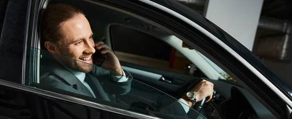 Cheerful elegant man talking happily by phone behind steering wheel, business concept, banner — Stock Photo